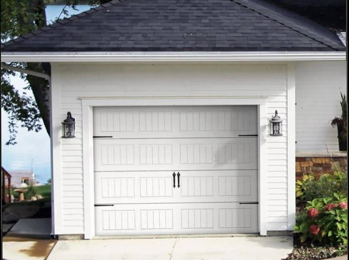 White carriage-style garage door on a lakeside home, installed with matching hardware