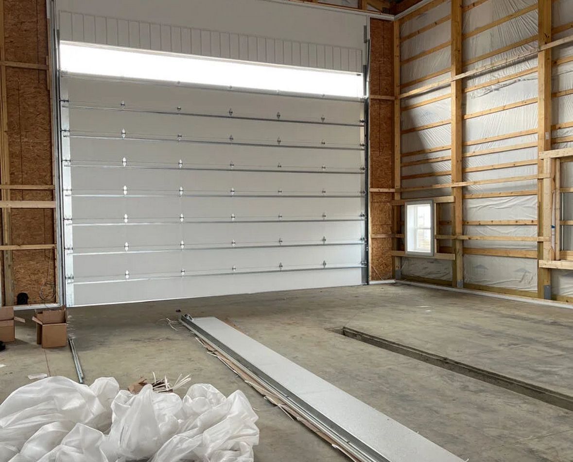New sectional garage door track and panel being fitted into a framed-out garage during a new install